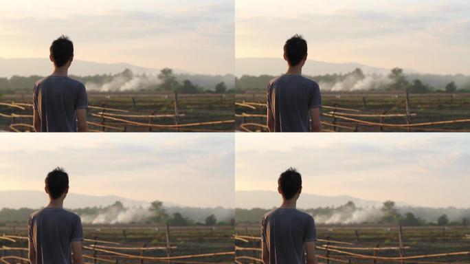 一个男孩看着农民在农田里烧麦茬