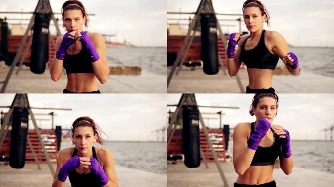 年轻女子双手裹着紫色拳击带练习拳击