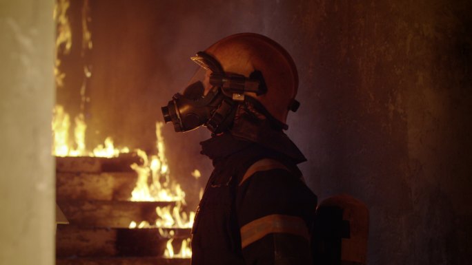 一位勇敢的消防队员视察燃烧着的建筑物