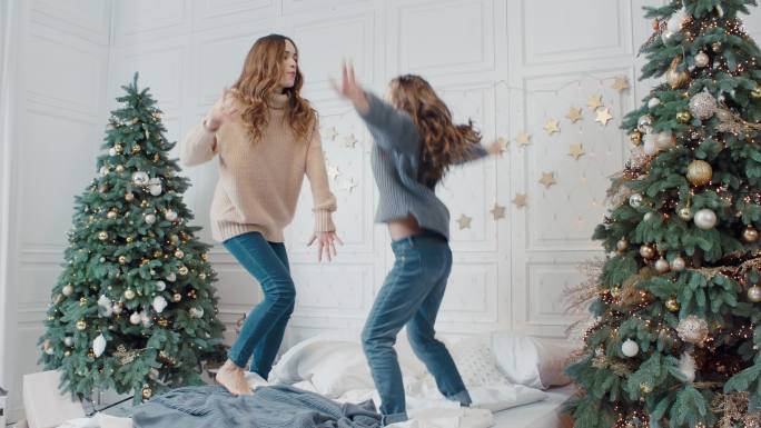 母女在床上蹦蹦跳跳庆祝圣诞节