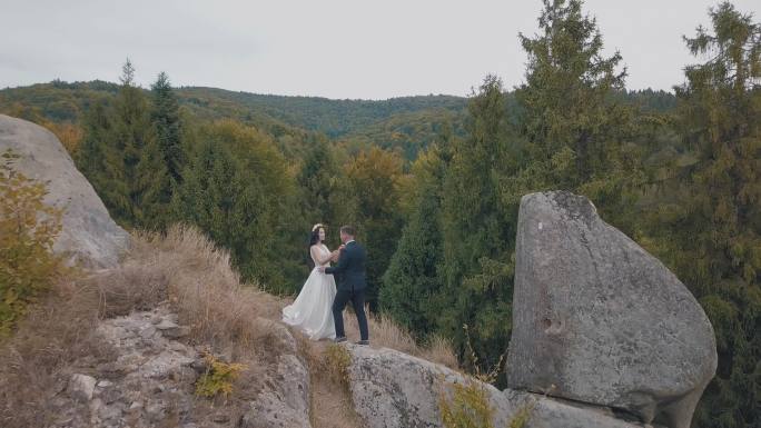 新婚夫妇站在山的高坡上。