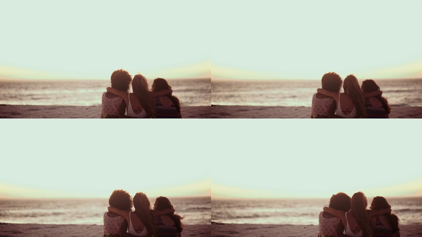 三个朋友坐在一起看海滩上的日落