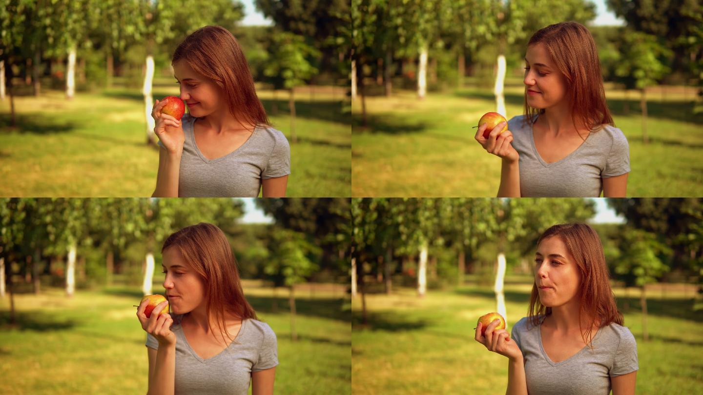 年轻女子在花园里吃着红苹果