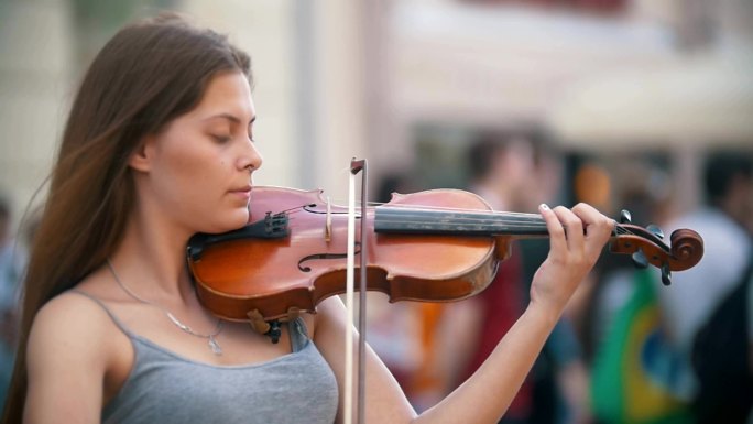 年轻的女子在步行街上拉小提琴