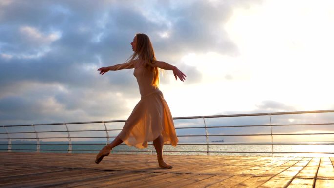 在日落时芭蕾舞演员在海堤上跳舞