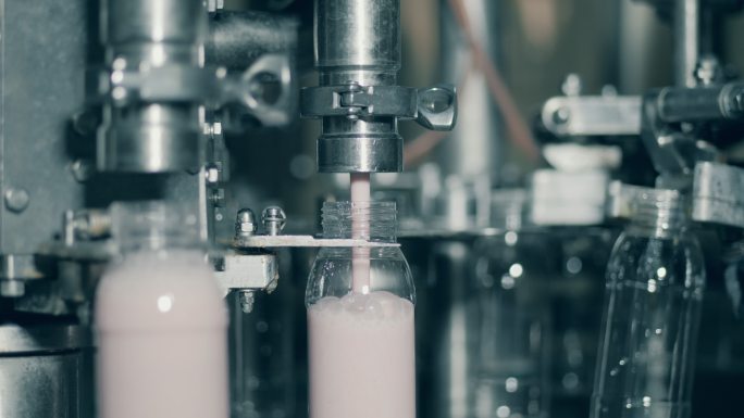 工厂机器用酸奶填充瓶子。
