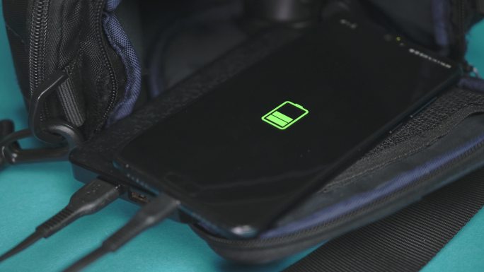 手机是通过背包上的电源盒充电的。