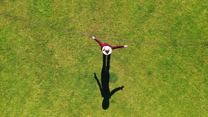 一名女子在绿草上旋转的鸟瞰图