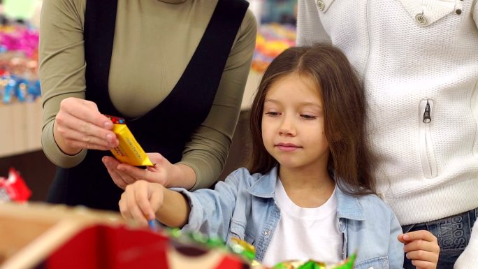 一个快乐的家庭和一个孩子在超市买糖果。