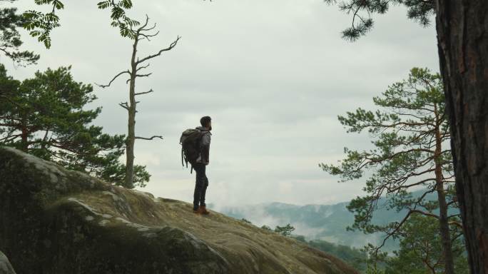 一个人站在悬崖顶上，看着大自然。
