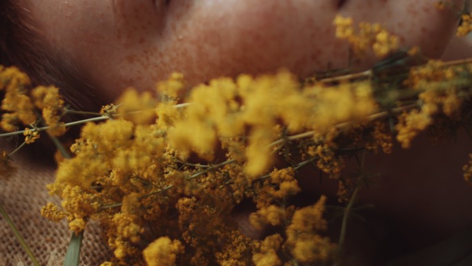 女人躺在地上拿着黄色的野花
