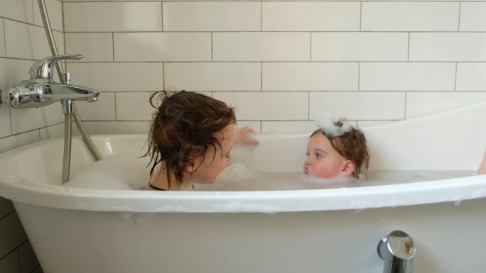 快乐的学龄前儿童在浴缸里互相交谈