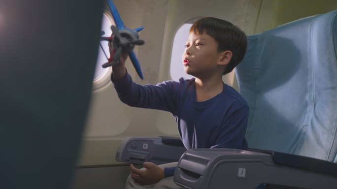 小男孩坐在飞机上玩飞机模型玩具