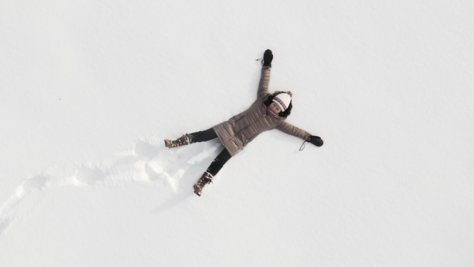 女人在雪中玩耍航拍下雪雪地摇摆