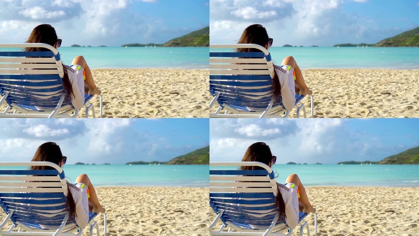 在热带海滩躺椅上晒日光浴的女人