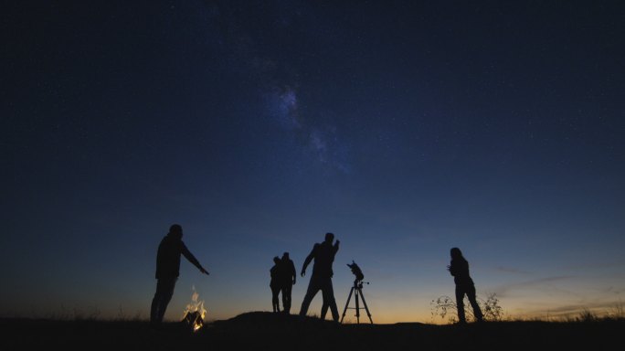 朋友们在夜晚用专业望远镜一起凝视银河