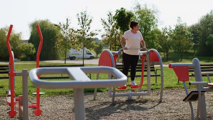 一名女子在公园使用椭圆训练器