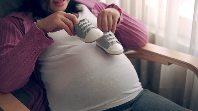 年轻母亲怀着孩子孕妇肚子月子中心胎教母婴