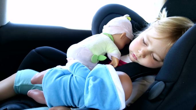 婴儿和娃娃睡在汽车座椅上