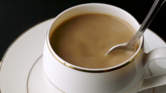 用勺子在白色杯子中搅拌咖啡