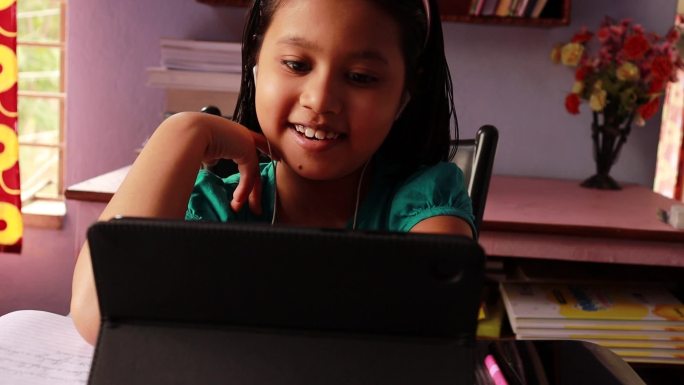 女孩在平板电脑前微笑着参加在线课程