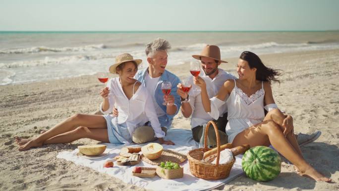 快乐的朋友在夏日海滩派对或野餐时吃早餐