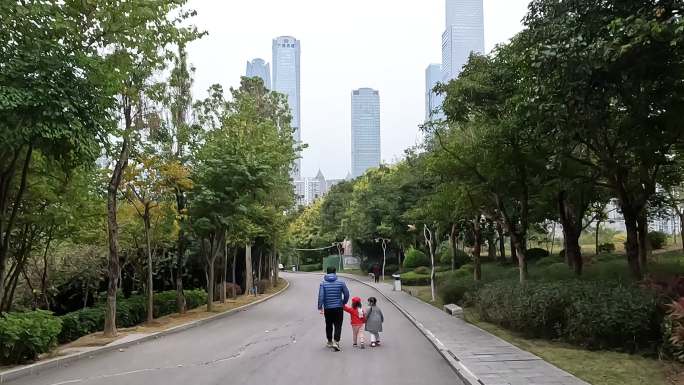 青年男性带两个小女孩在儿童公园散步踏青