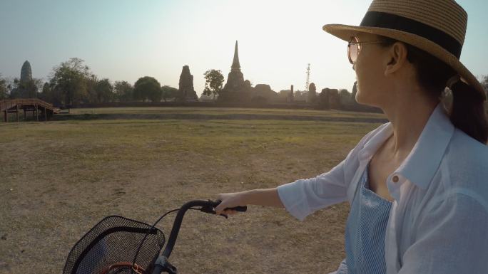 戴着宽边帽和太阳镜的女人骑着自行车
