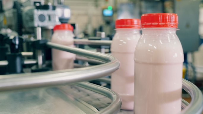 工厂生产线上瓶装白色酸奶。