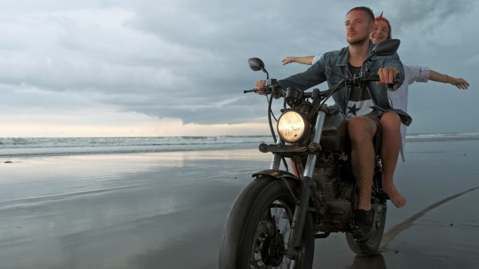 情侣在海滩上骑着复古摩托车