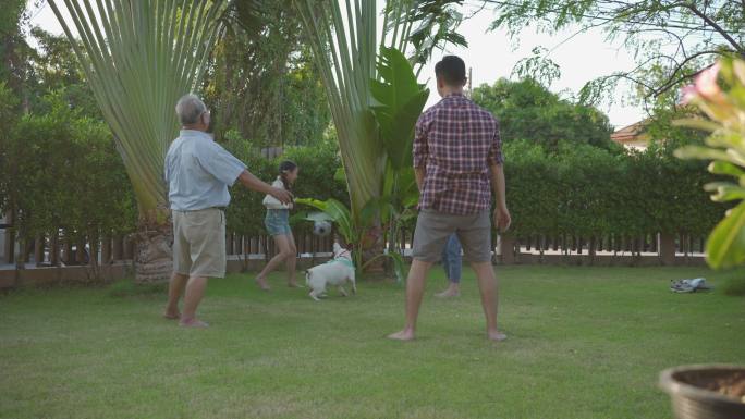 快乐的家庭和他的狗在花园里踢足球。