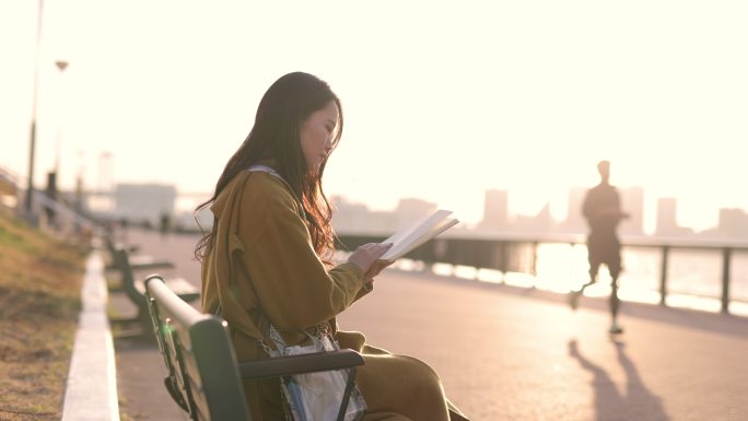 日落时分，年轻女子在海滨公园看书