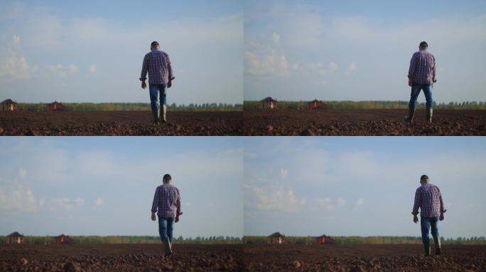 农夫穿着橡胶靴走在绿色的田野上