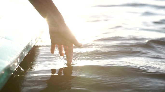 日落时，特写一个女孩在水中的手