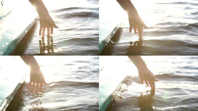 日落时，特写一个女孩在水中的手