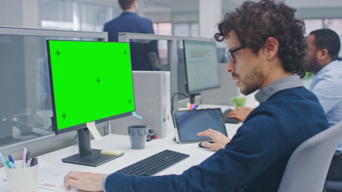 经理在带有绿色屏幕模型的台式电脑上工作。