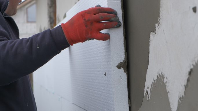 建筑工人在房屋外墙上安装泡沫塑料隔热板