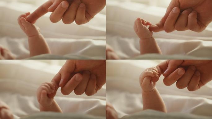 新生儿躺在婴儿床上握住母亲的手指