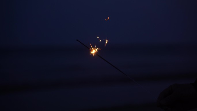 跨年海滩手持烟花绚烂光芒远方天际火花大海