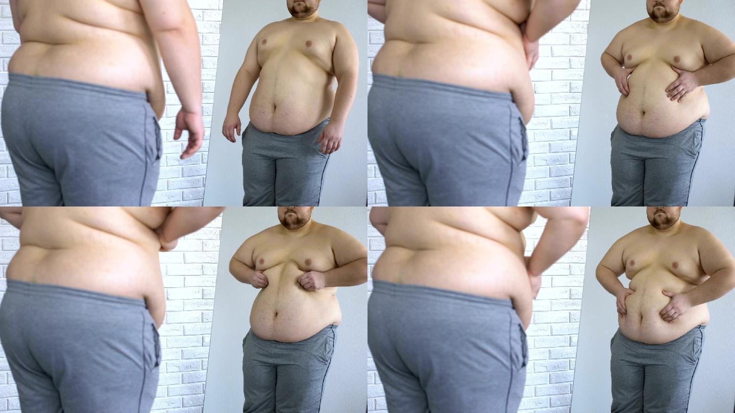 男性在镜子里检查自己肥胖的身体