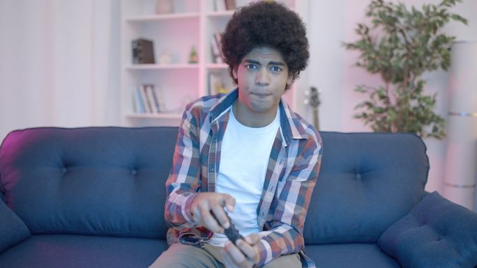 男青少年情绪化地在沙发上玩电子游戏