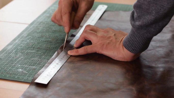 制革工人用尺子和锥子在棕色皮革上做标记