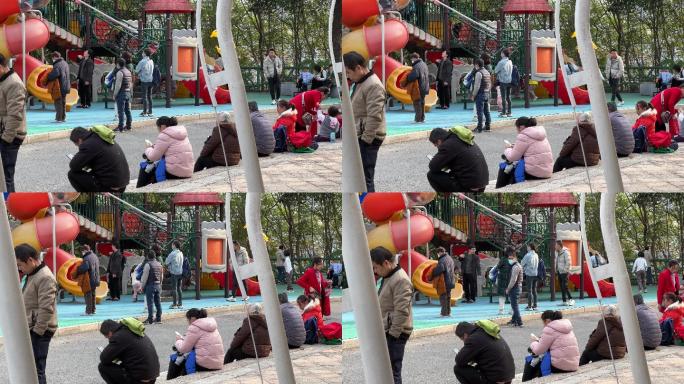 春天在公园里遛娃的家长们在低头看手机