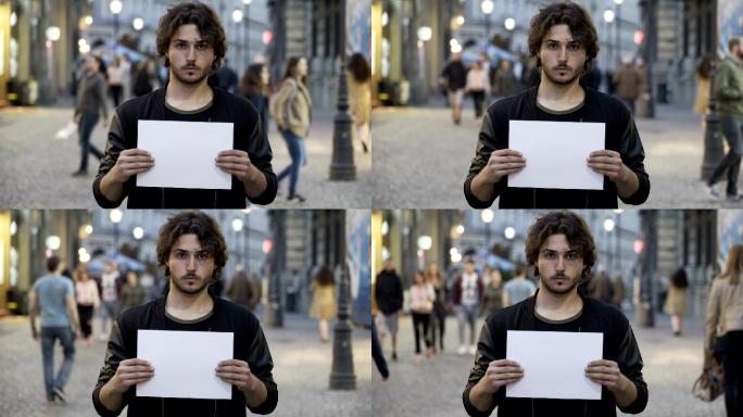 年轻人在街上举着一张空白的纸
