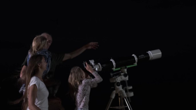 幸福的家庭通过望远镜在夜空中看月亮和星星