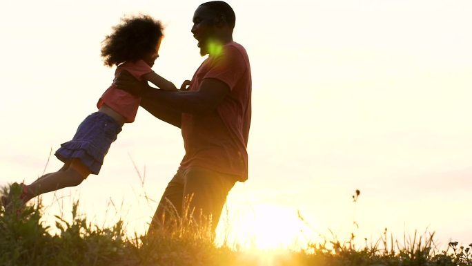 爸爸和他的小女儿在明亮的夕阳中玩耍