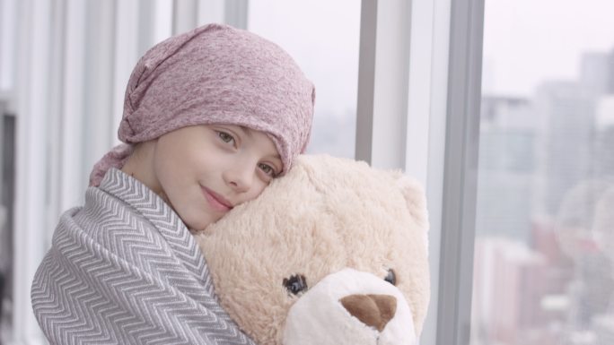 一个癌症女孩手持填充玩具的肖像