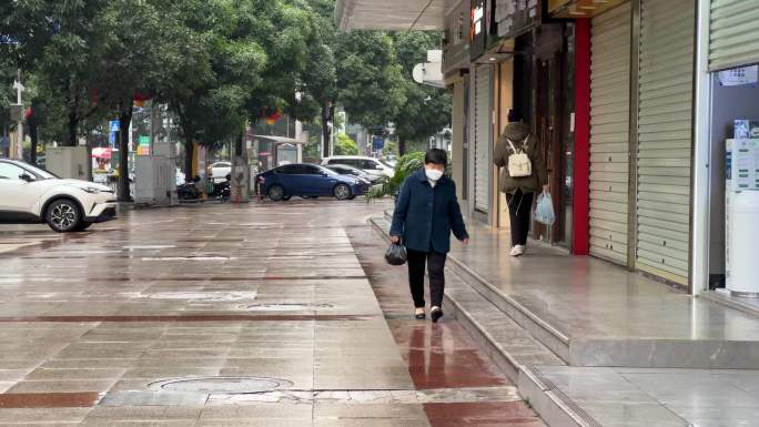 清晨雨后买菜的老年妇女走在大街上