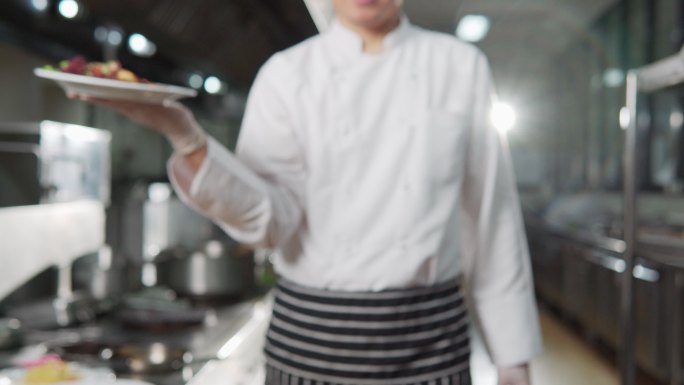 男厨师的肖像，向镜头展示一盘食物
