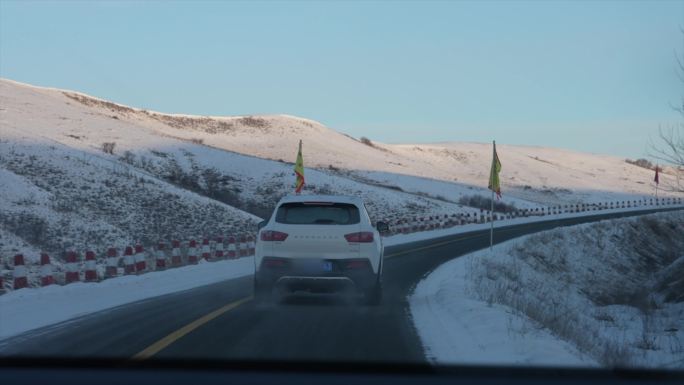汽车在雪山下的公路上驰骋跟拍镜头